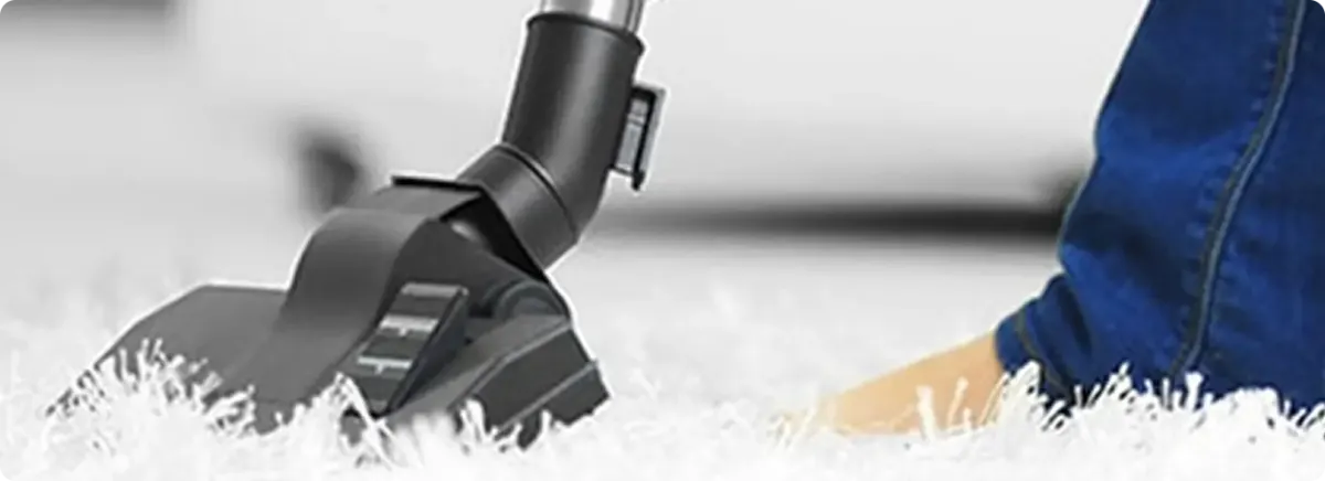 Close-up of a professional vacuuming a white carpet in Jber.